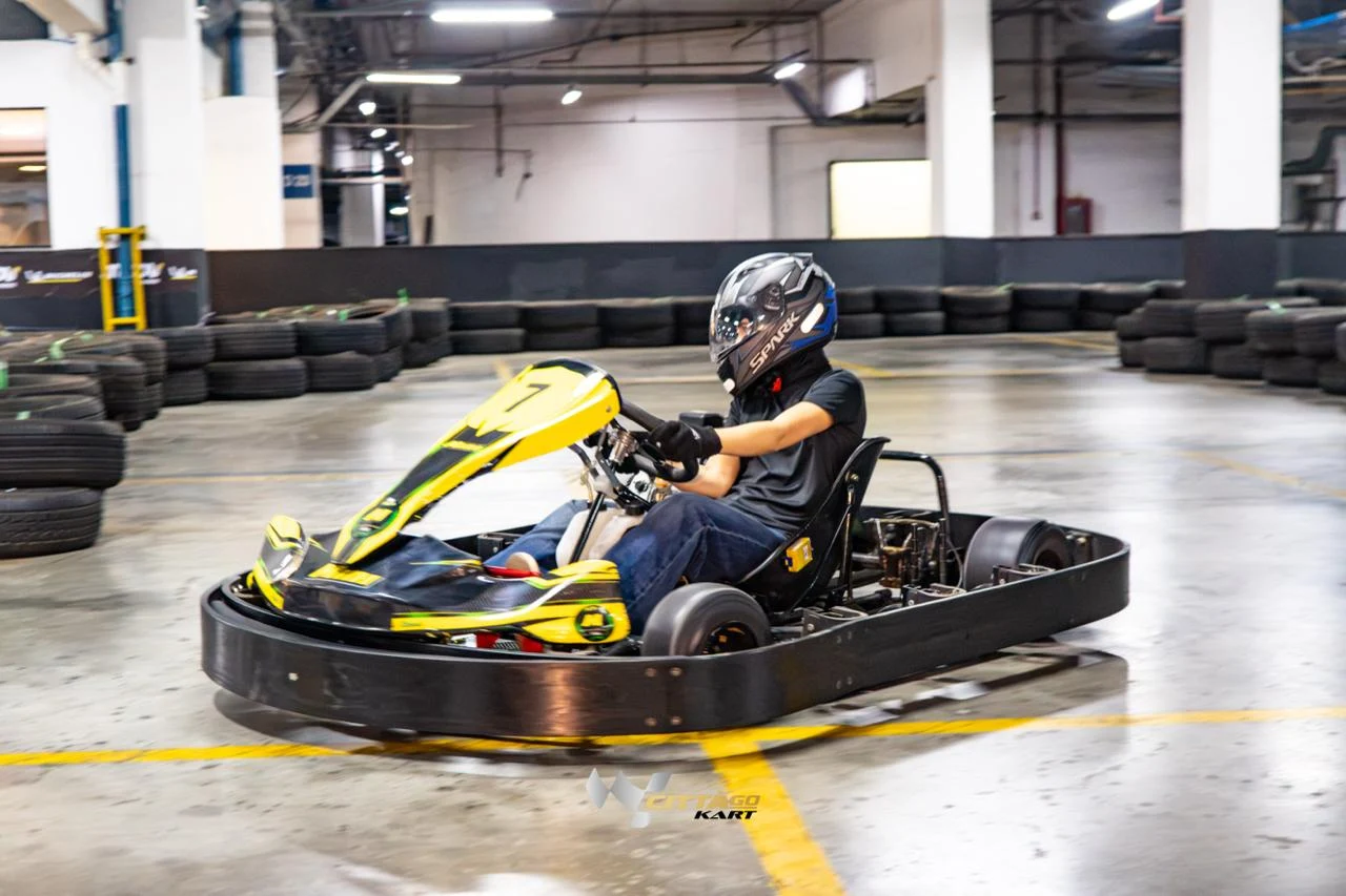 Piloto contornando uma curva em um kart amarelo e preto do Città